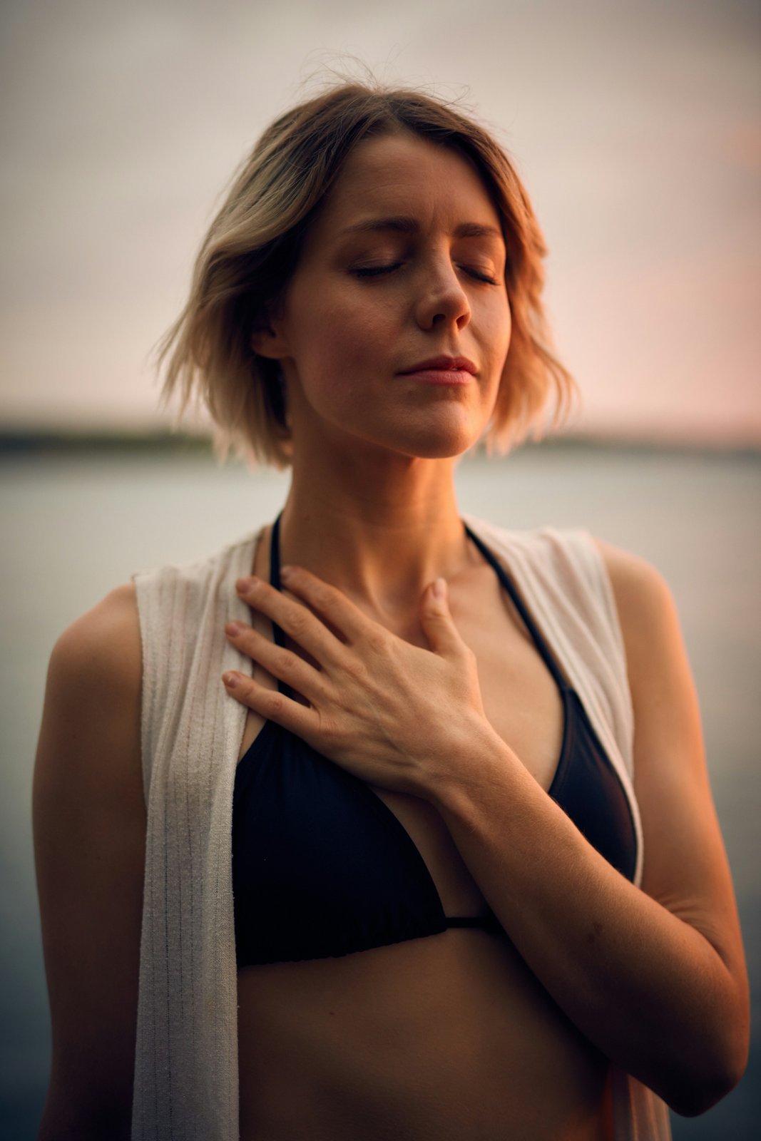 Woman with hand on chest, eyes closed — humming and parasympathetic activation enjoying a peaceful summer moment in Edmonton — Body In Fushion