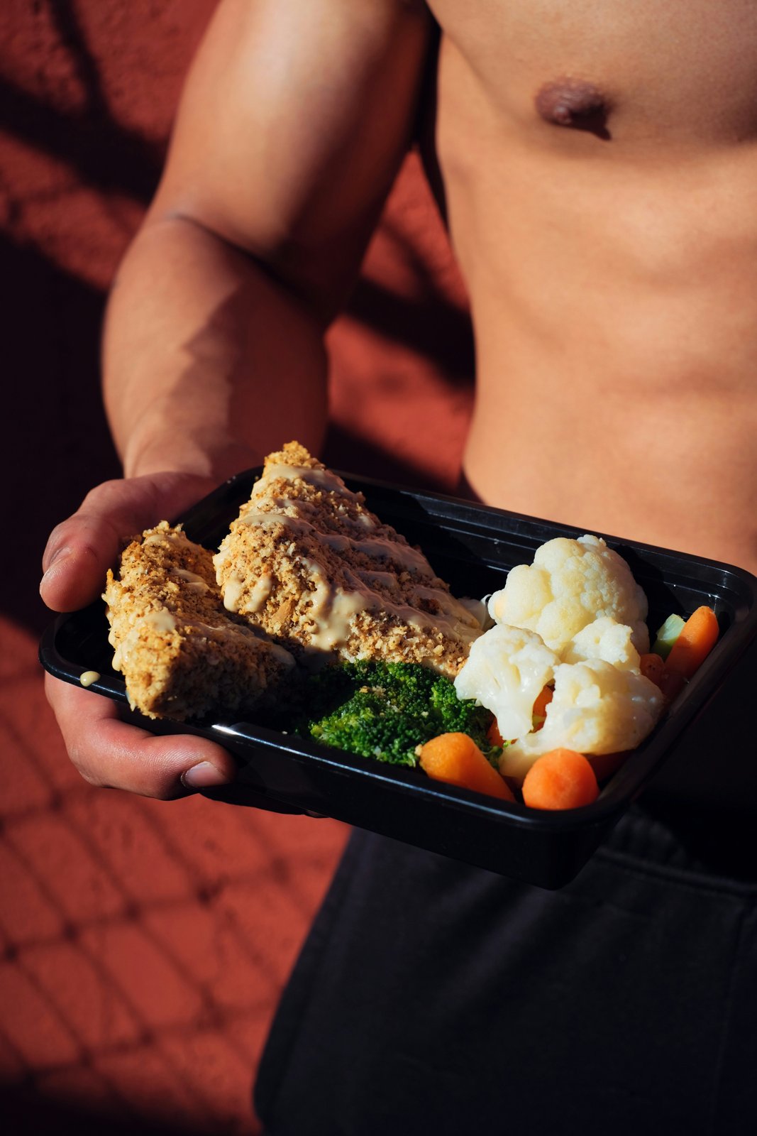 Athlete holding a meal-prep container with lean protein — how much protein per day