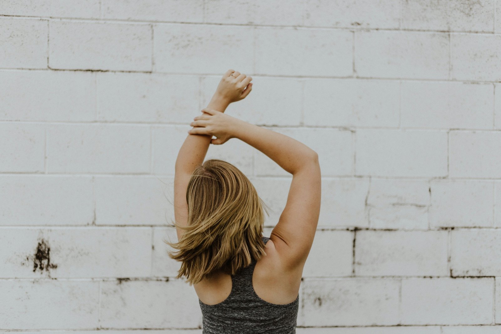 Woman stretching against a white brick wall — five-minute parasympathetic recovery